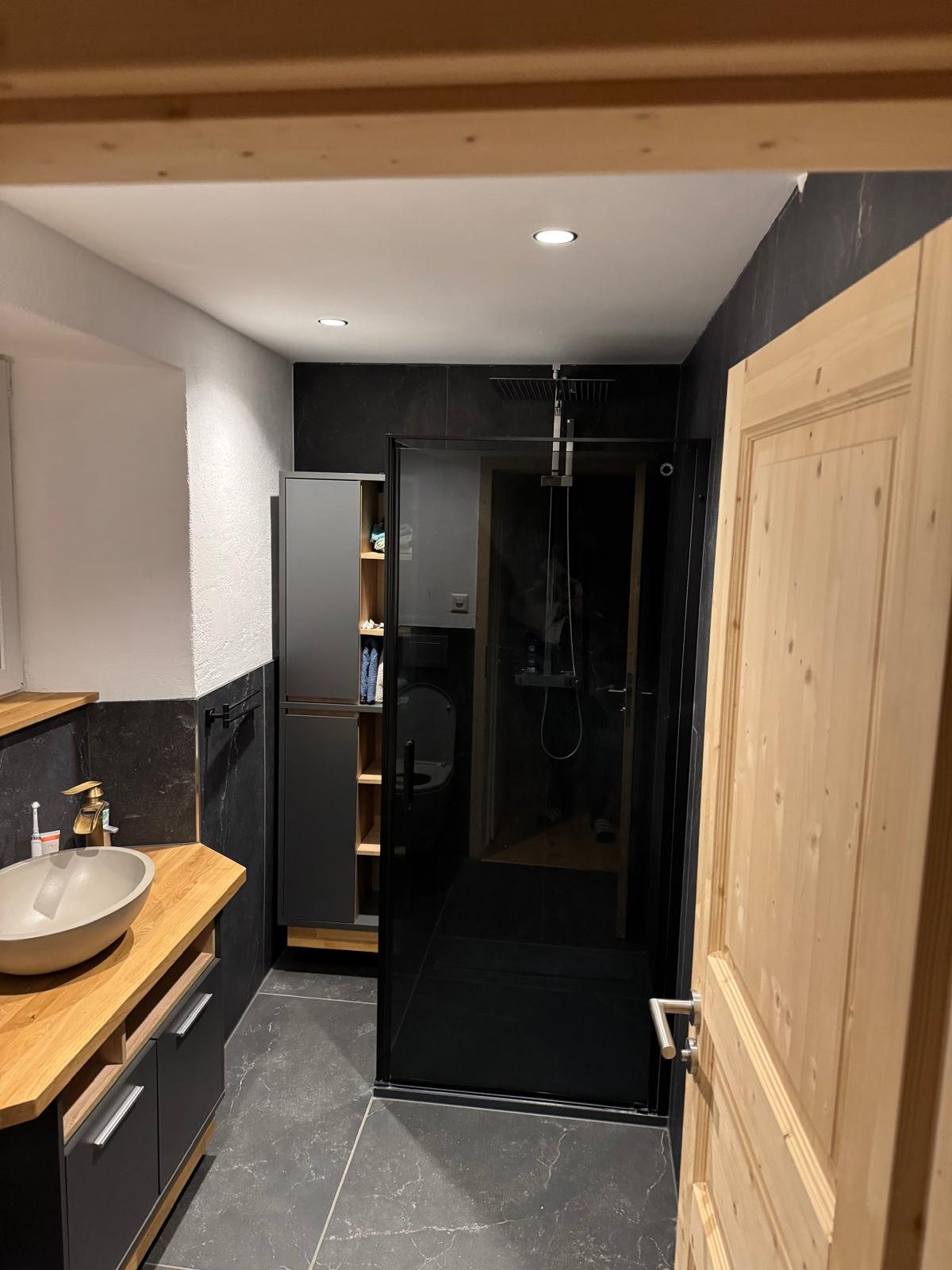 Fertiges Badezimmer mit Holzwaschtisch und dunkler Keramik